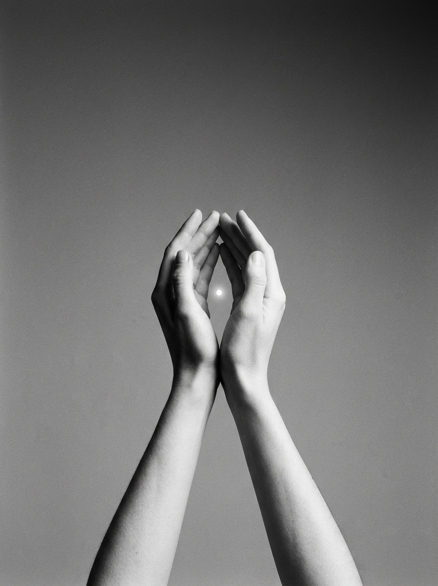 Two cupped hands holding a single small point of light